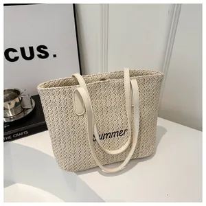 Détail de la broderie Summer sur un sac cabas tissé beige avec anses en cuir blanc