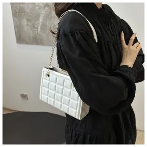 Detalle de bolso acolchado blanco con cadena dorada y herrajes metálicos en el hombro