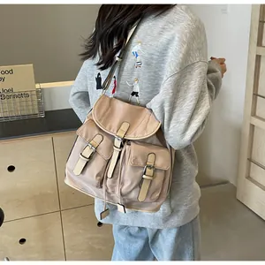 Detail of khaki canvas backpack featuring leather buckles and multiple utility pockets