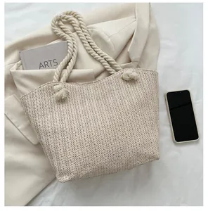 Detail of herringbone woven texture and thick white cotton rope handles on straw tote