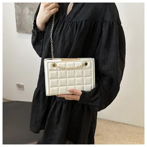 Detalle de la textura acolchada blanca con cadena dorada en bolso bandolera