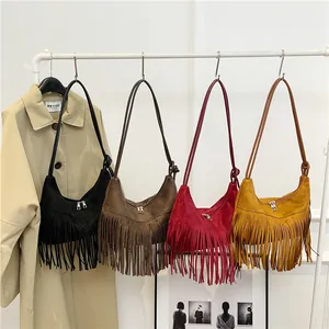 Bohemian suède schoudertassen met franjes in vier vintage kleuren aan een rek