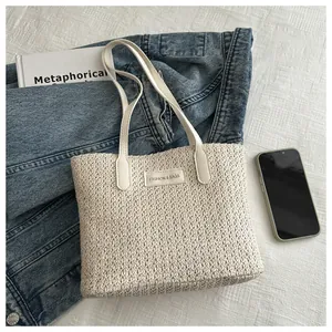 Close-up of woven straw tote bag with a fashion logo patch on casual background