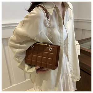 Primer plano de bolso acolchado marrón con cadena dorada usado por una modelo