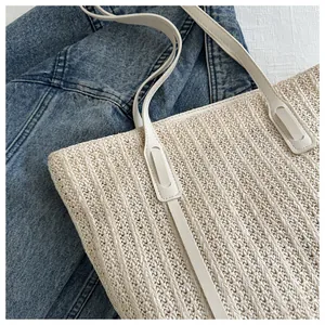 Detail of woven straw tote bag with cream leather straps and fine vertical texture