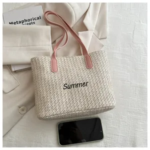 Détail du sac cabas en paille beige avec broderie Summer noire et anses en cuir rose