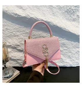 Détail d'un sac à main rose en strass avec logo S doré et élégante décoration de gland