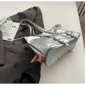 Detailed view of silver metallic tote bag with buckle straps and side zipper accents