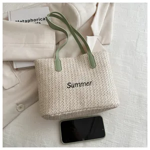 Vue détaillée de la texture de paille beige et de la broderie noire Summer sur le sac cabas