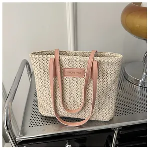 Detail of straw woven tote bag featuring pink handles and a Fashion & Bags label tag