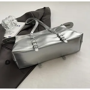 Macro detail of silver metallic tote bag with buckle straps and glossy PU leather texture