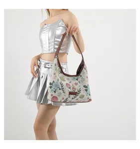 Detail of floral jacquard embroidery and brown faux leather strap on shoulder bag