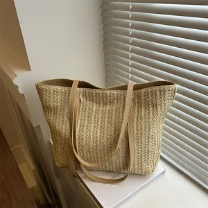 Minimalist straw tote bag in beige with brown leather handles for summer vacation