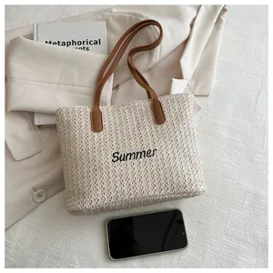 Détail du sac cabas en paille tissée avec broderie Summer et anses en cuir marron