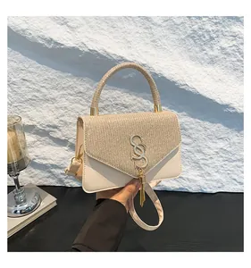 Détail d'un sac en cuir beige avec rabat en strass et logo S en métal doré