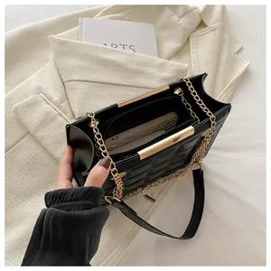 Detalle de bolso acolchado negro con cadena dorada y compartimento interno con cremallera