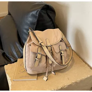 Detail view of beige canvas backpack with leather straps and front pockets on stone decor