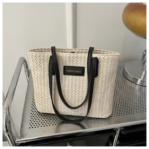 Detailed straw weave texture on a beige tote bag with black leather straps and logo