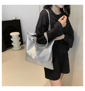 Silver metallic tote bag with geometric stitching shown on a model in a minimalist setting