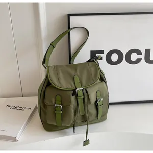 Detail view of an olive green canvas backpack with leather straps and front pockets
