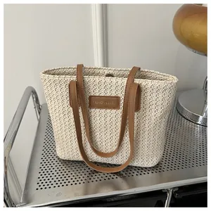 Detailed view of woven straw tote bag featuring leather handles and magnetic closure