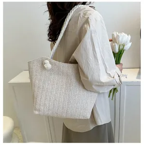 Detailed shot of beige woven tote bag with herringbone pattern and rope shoulder strap