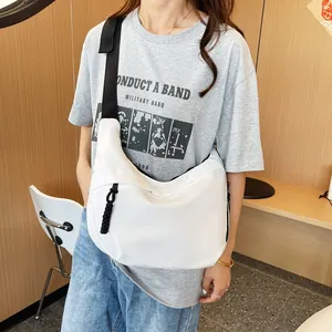 White nylon crossbody bag shown worn by a model in a natural light indoor setting