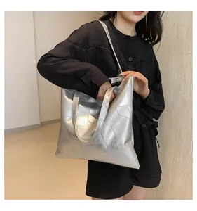 Detail shot of a silver metallic tote bag with geometric stitching on a female model