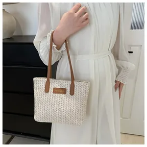 Detail of summer straw tote bag with brown leather handles and fashion logo patch