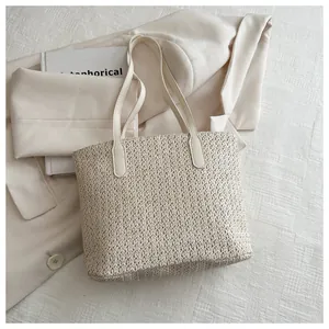 Gros plan du sac cabas en paille tressée crème avec anses en similicuir lisse