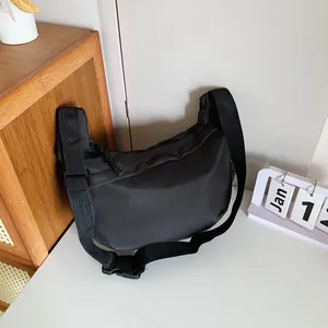 Detail of minimalist black nylon dumpling bag with adjustable strap and buckle closure