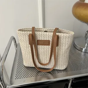 Chic woven straw tote bag with brown leather handles and fashion logo patch