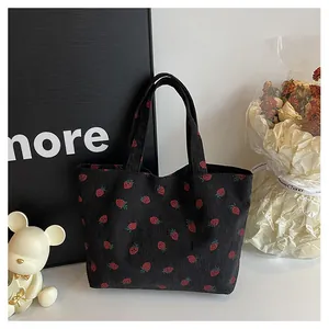 Détail du sac fourre-tout en velours côtelé noir avec motifs fraises rouges et anses assorties