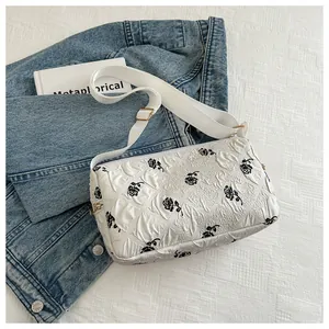 Detail of floral tote bag showing black rose pattern on white bubble textured fabric
