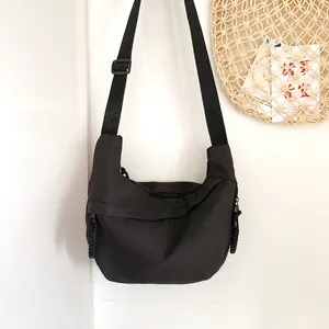 Detail of minimalist black nylon crescent crossbody bag with adjustable strap and rope zipper