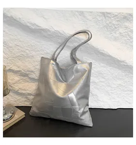 Detail of silver metallic tote bag featuring rectangular stitching and reflective texture