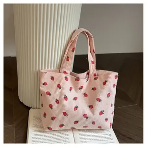 Détail du sac en velours côtelé rose avec motifs fraises rouges et texture douce