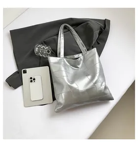 Detail of silver metallic tote bag featuring square quilted texture and spacious interior