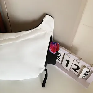 Detail view of white crescent bag side pocket with a card and black zipper accent