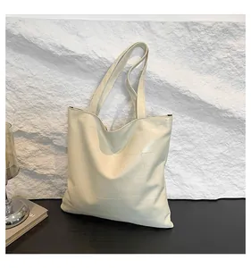 Detail view of cream tote bag featuring unique geometric patchwork stitching and soft leather