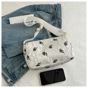 Detail of white floral shoulder bag with black rose print and gold metal buckle