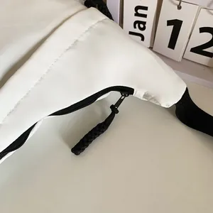 Close-up of white sporty tote bag with black zipper detail and textured weave puller