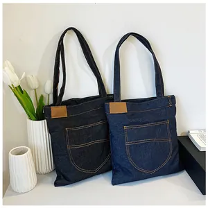 Detail showing denim tote bag texture with contrast stitching and brown leather label