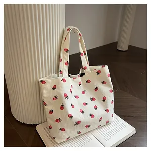 Détail d'un sac cabas en velours côtelé crème avec motif fraises sur parquet
