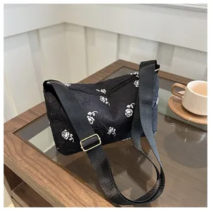 Detail of black floral jacquard shoulder bag with white rose pattern and golden buckles