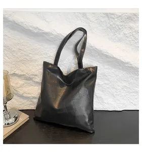 Detailed close-up of a black leather tote bag with unique irregular stitched texture