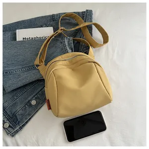Vista dall'alto di borsa a tracolla in nylon giallo con giacca di jeans e accessori