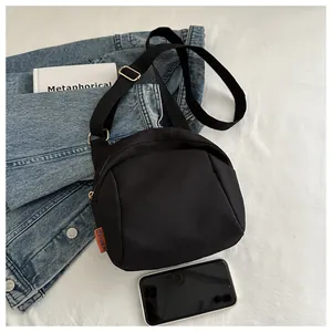 Dettaglio della borsa a tracolla in nylon nero a mezzaluna con etichetta arancione alla moda