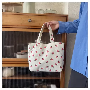 Détail de la texture d'un sac cabas en velours côtelé avec imprimé fraises rouges