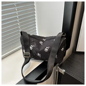 Detailed view of black floral jacquard tote bag with white rose pattern and wide strap